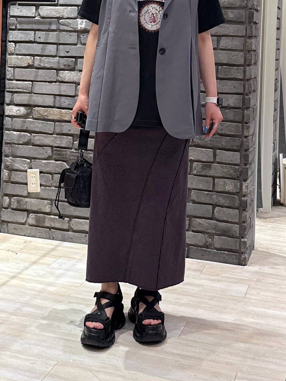 ブラック系のサンダル、ブラック系のショルダーバッグ、グレー系のベストを着用したレディースの春コーディネートの4枚目の写真