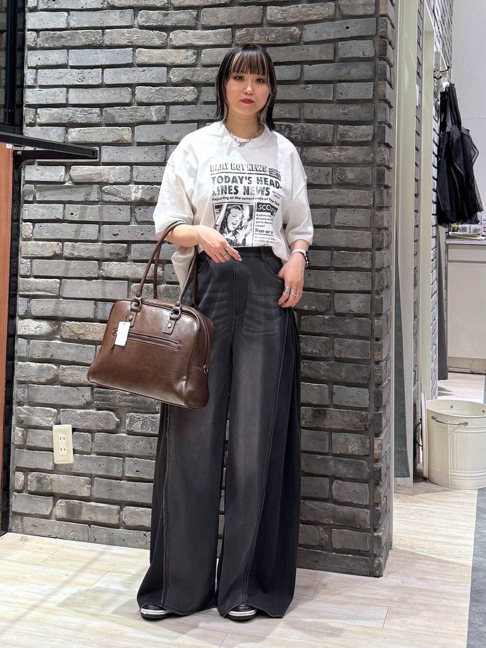 ブラウン系のボストンバッグ、ブラック系のデニムパンツ、ホワイト系のTシャツ/カットソーを着用したレディースの春コーディネートの2枚目の写真