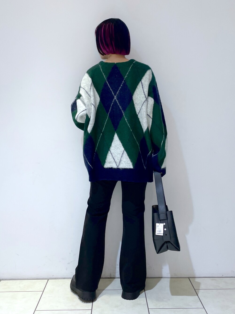 グリーン系のカーディガン/ボレロ、ホワイト系のキャミソール、ブラック系のスラックスを着用したレディースの秋コーディネートの2枚目の写真