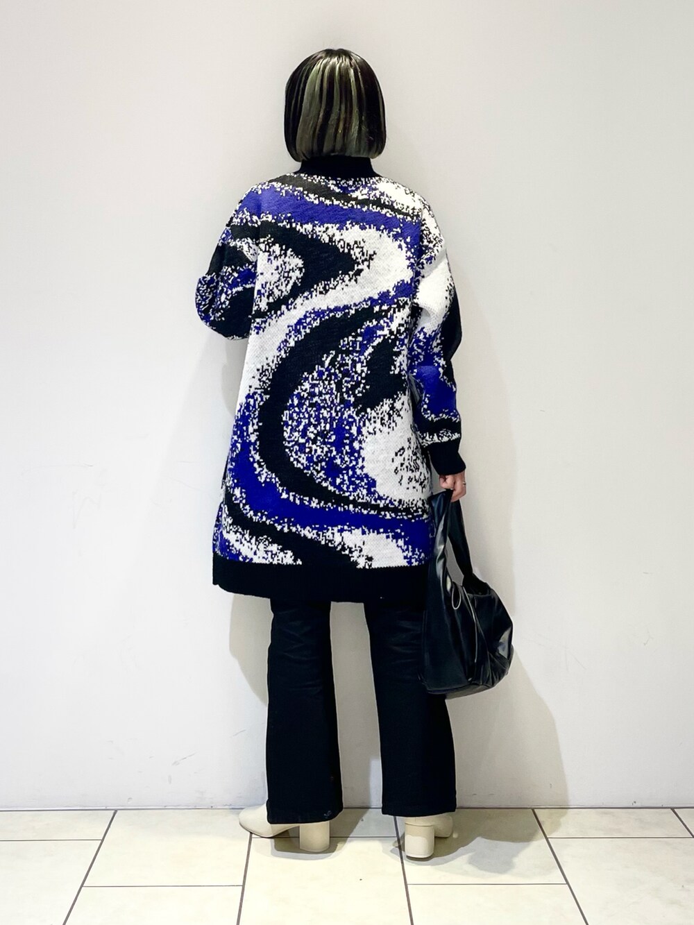 ブラック系のワンピース、ブラック系のデニムパンツ、ブラック系のハンドバッグを着用したレディースの冬コーディネートの2枚目の写真