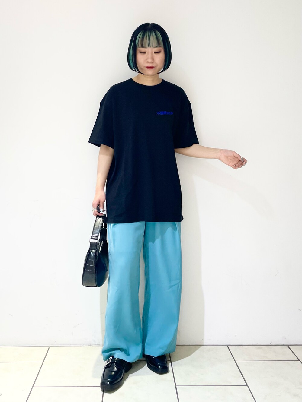 ブルー系のスラックス、ブラック系のショルダーバッグ、ブラック系のローファーを着用したレディースの夏コーディネートの4枚目の写真