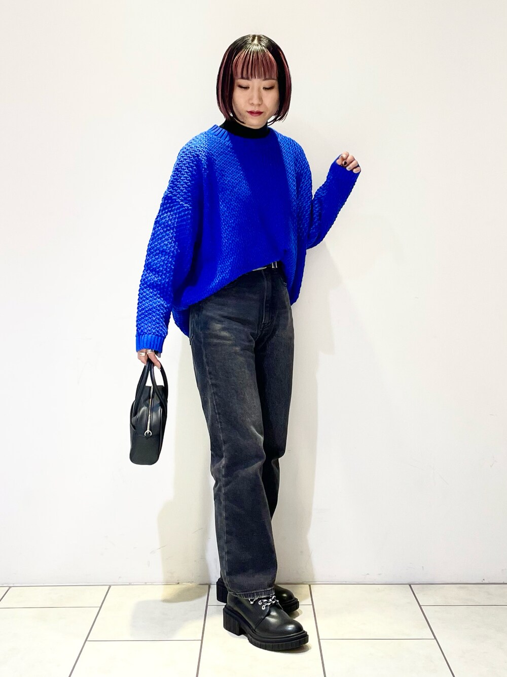 ブラック系のニット/セーター、ブルー系のニット/セーター、ブラック系のボストンバッグを着用したレディースの春コーディネートの2枚目の写真