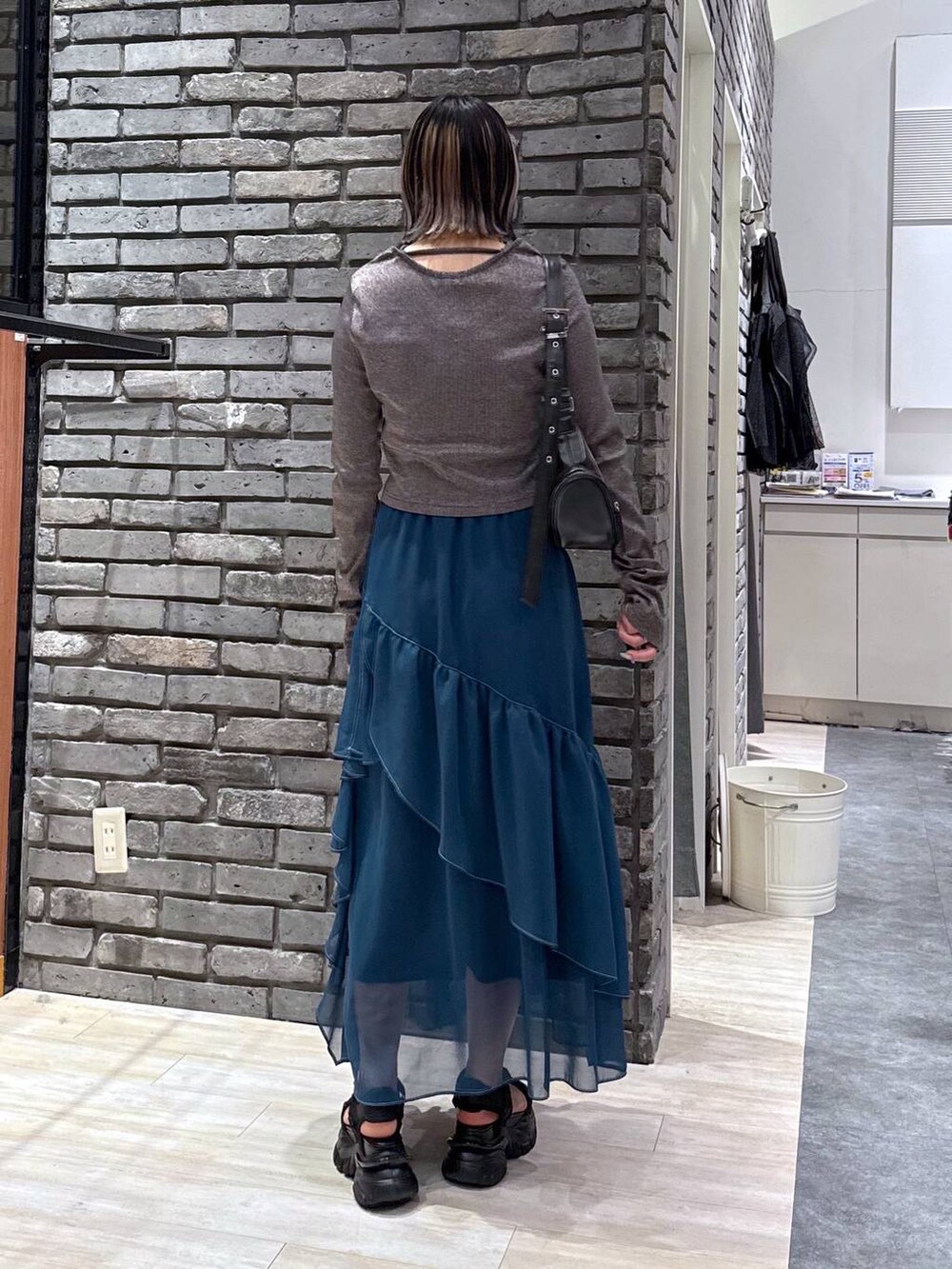 グリーン系のスカート、ブラック系のサンダル、ブラック系のショルダーバッグを着用したレディースの春コーディネートの5枚目の写真
