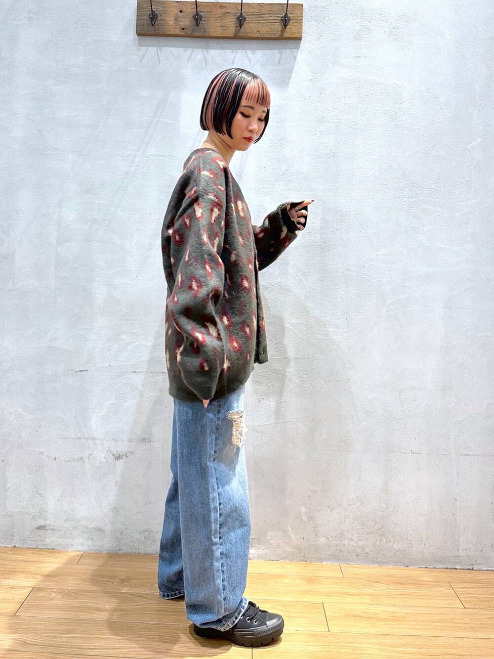 レッド系のカーディガン/ボレロ、ブルー系のデニムパンツ、シルバー系のネックレスを着用したレディースの秋コーディネートの3枚目の写真