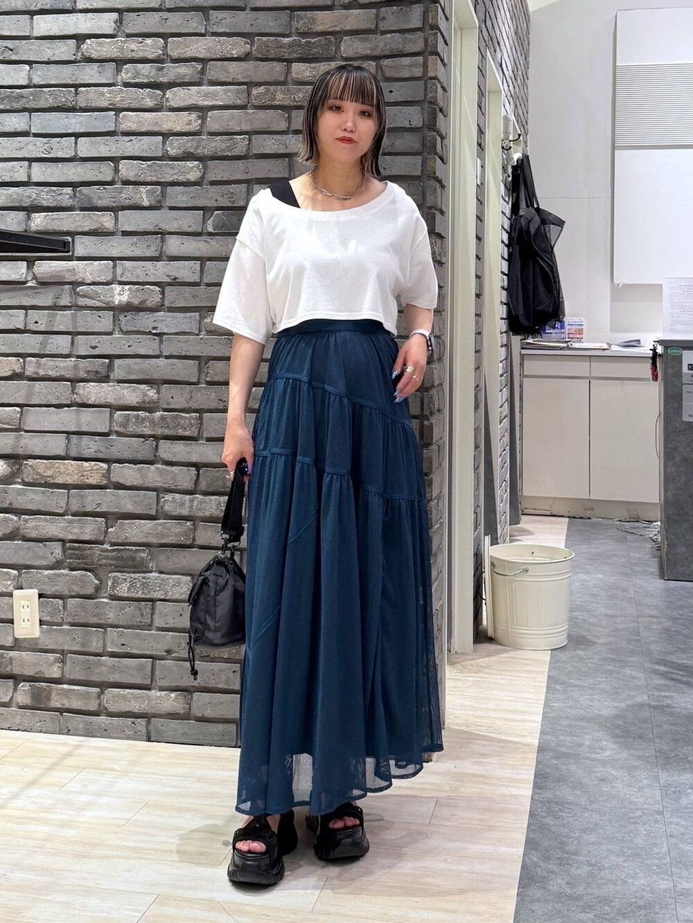 ブラック系のサンダル、ブラック系のショルダーバッグ、ブルー系のスカートを着用したレディースの春コーディネートの2枚目の写真