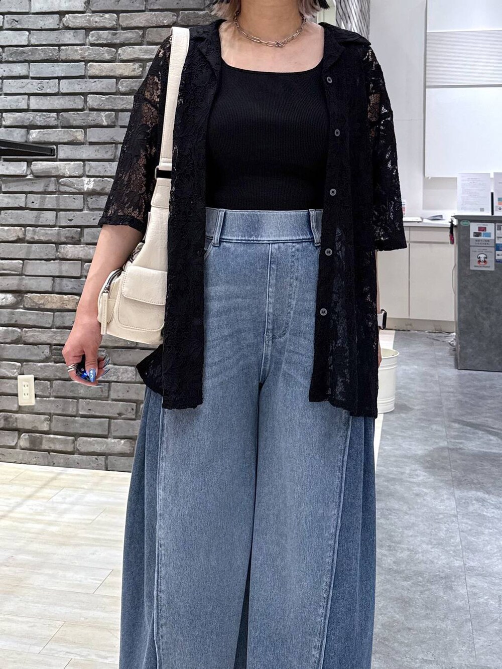 ブラック系のサンダル、ブルー系のデニムパンツ、ホワイト系のショルダーバッグを着用したレディースの春コーディネートの5枚目の写真