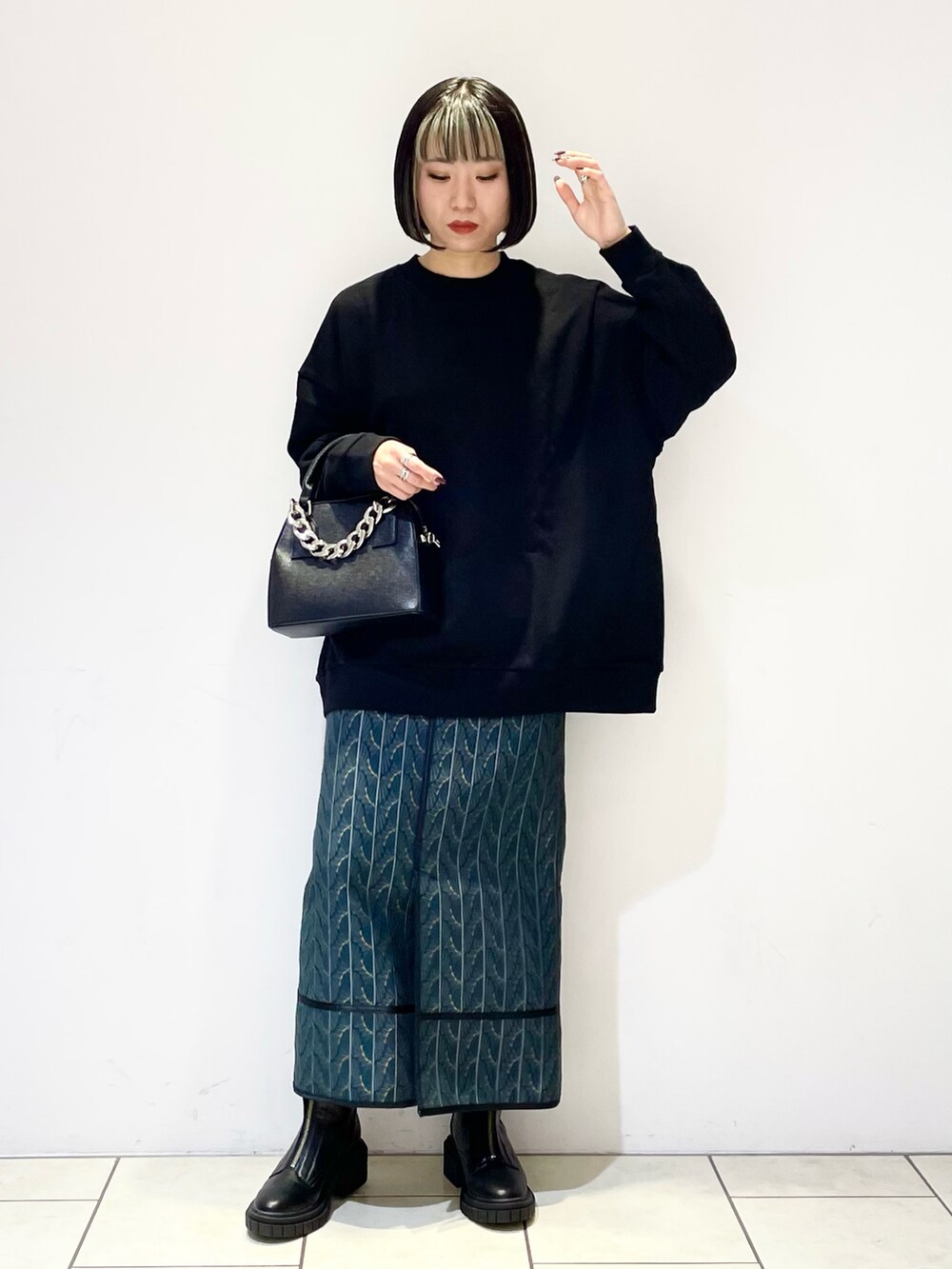 ブラック系のスウェット、ブラック系のショルダーバッグ、グリーン系のスカートを着用したレディースの冬コーディネートの2枚目の写真