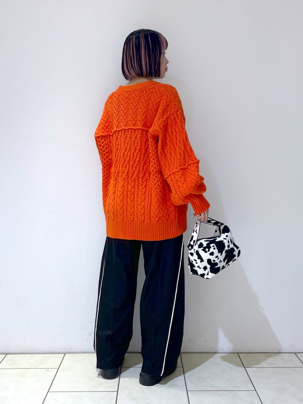 オレンジ系のカーディガン/ボレロ、ホワイト系のキャミソール、ブラック系のスラックスを着用したレディースの秋コーディネートの4枚目の写真