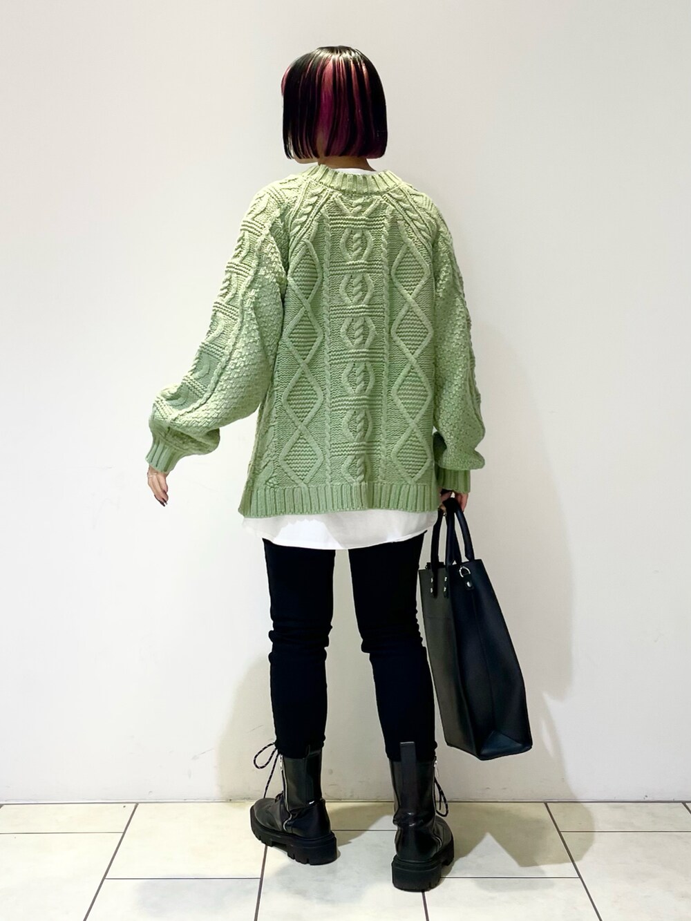 グリーン系のニット/セーター、ホワイト系のTシャツ/カットソー、ブラック系のデニムパンツを着用したレディースの冬コーディネートの4枚目の写真
