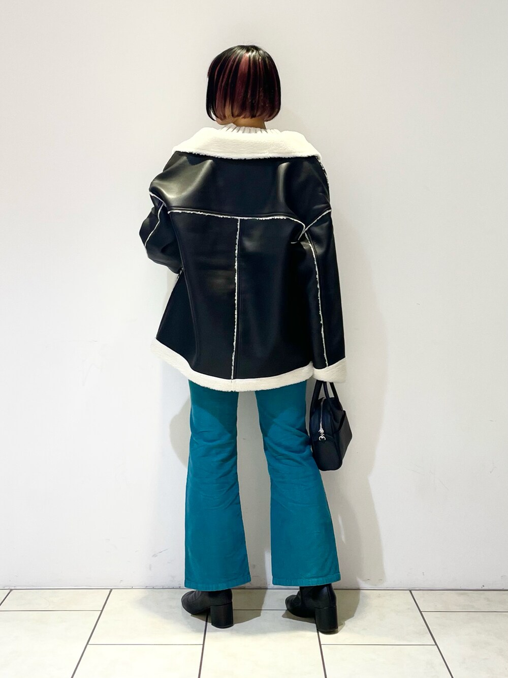 ブラック系のブルゾン、ベージュ系のニット/セーター、ホワイト系のTシャツ/カットソーを着用したレディースの冬コーディネートの3枚目の写真