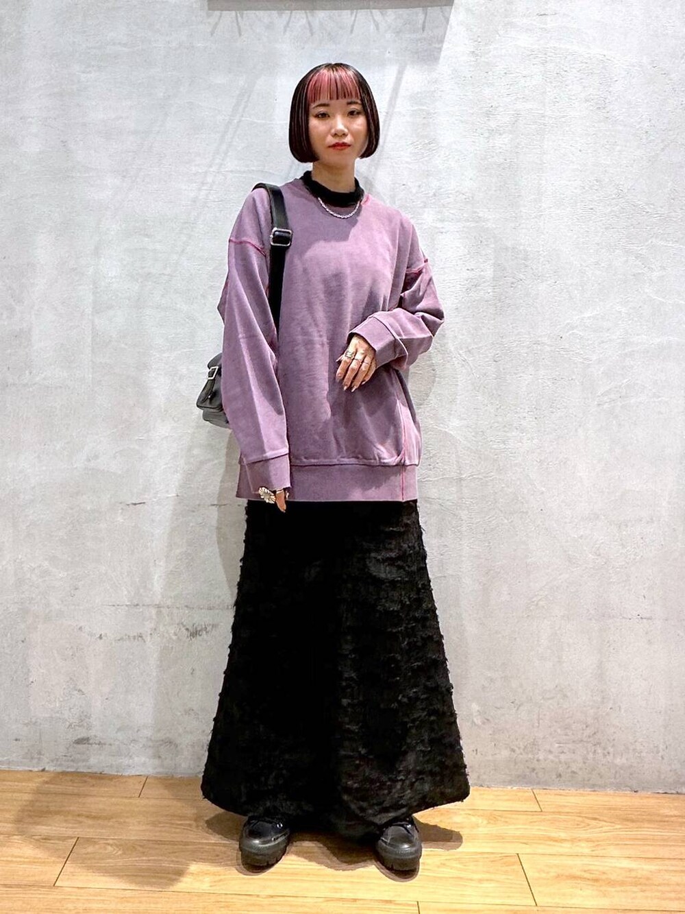 パープル系のスウェット、ブラック系のショルダーバッグ、ブラック系のワンピースを着用したレディースの秋コーディネートの2枚目の写真