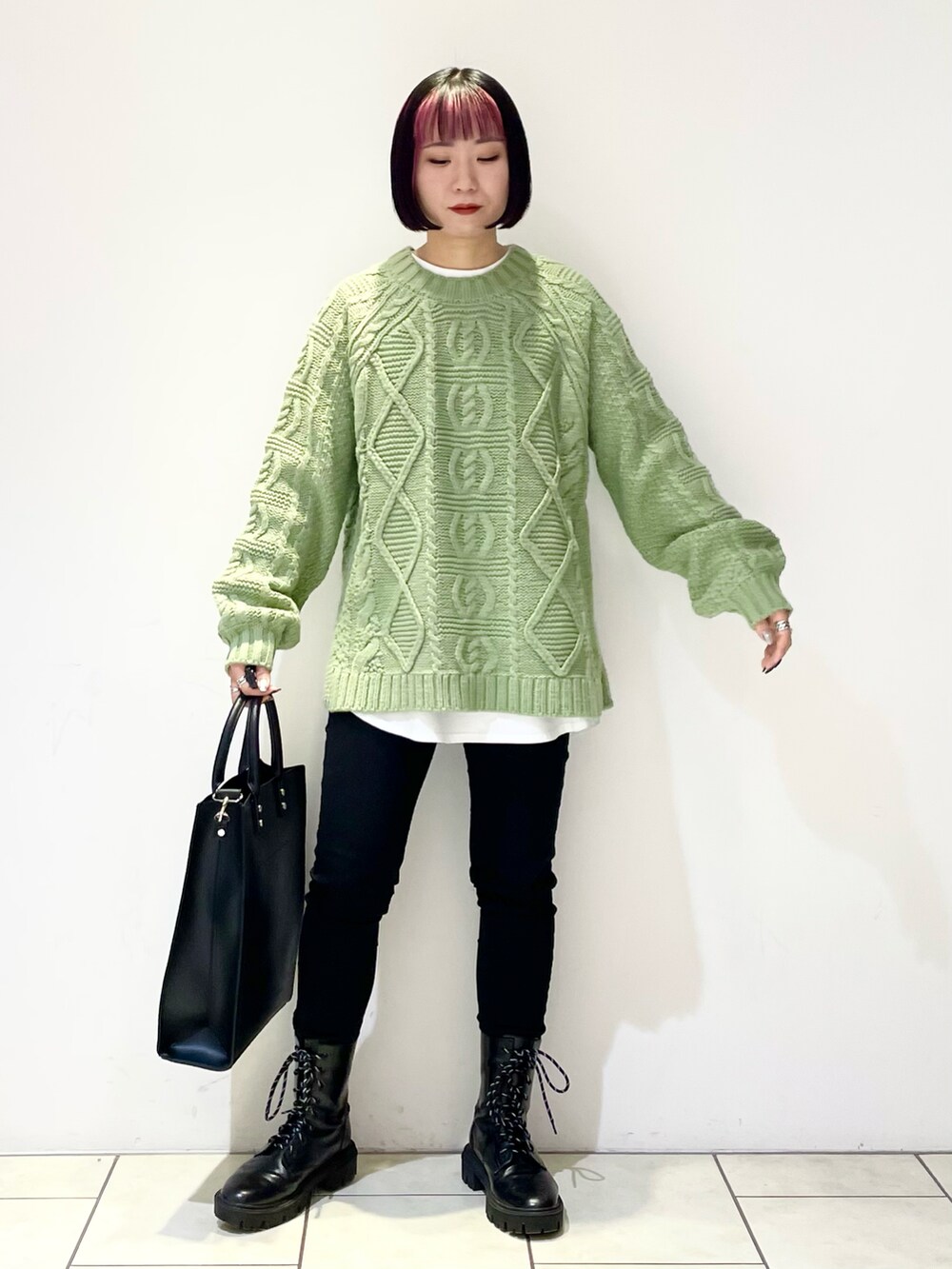 グリーン系のニット/セーター、ホワイト系のTシャツ/カットソー、ブラック系のデニムパンツを着用したレディースの冬コーディネートの2枚目の写真