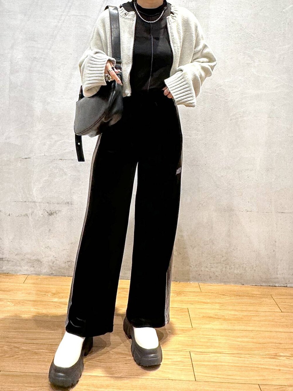 ホワイト系のブーツ、ブラック系のショルダーバッグ、ブラック系のその他パンツを着用したレディースの秋コーディネートの6枚目の写真