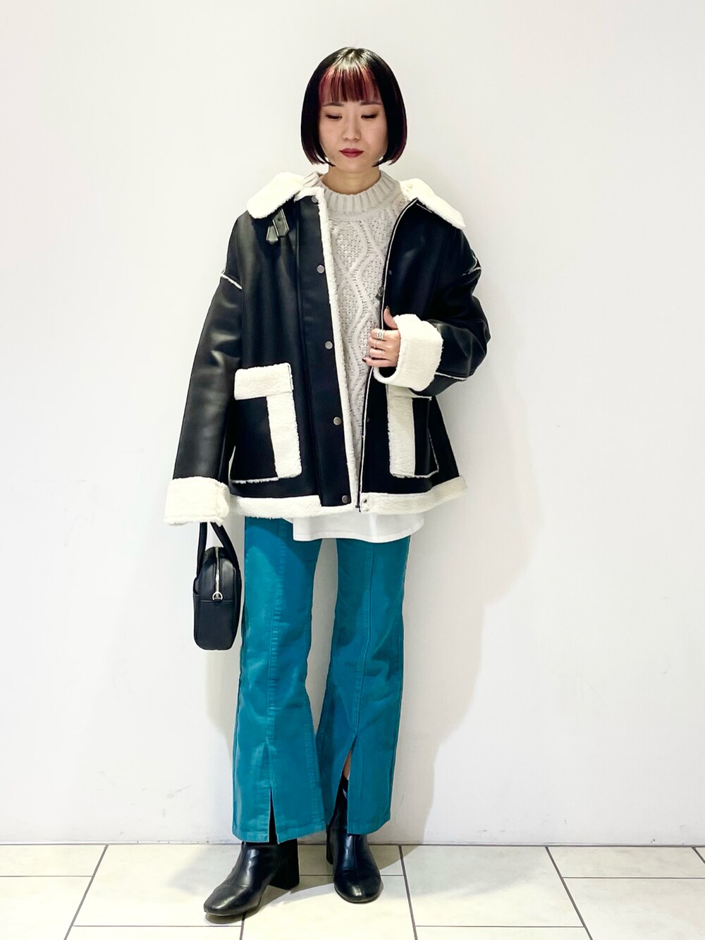 ブラック系のブルゾン、ベージュ系のニット/セーター、ホワイト系のTシャツ/カットソーを着用したレディースの冬コーディネートの2枚目の写真