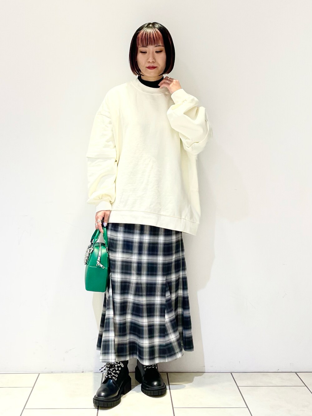 ホワイト系のスウェット、ブラック系のニット/セーター、グリーン系のショルダーバッグを着用したレディースの春コーディネートの2枚目の写真