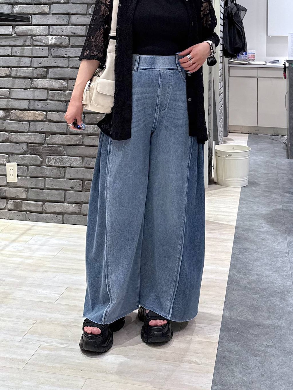 ブラック系のサンダル、ブルー系のデニムパンツ、ホワイト系のショルダーバッグを着用したレディースの春コーディネートの6枚目の写真