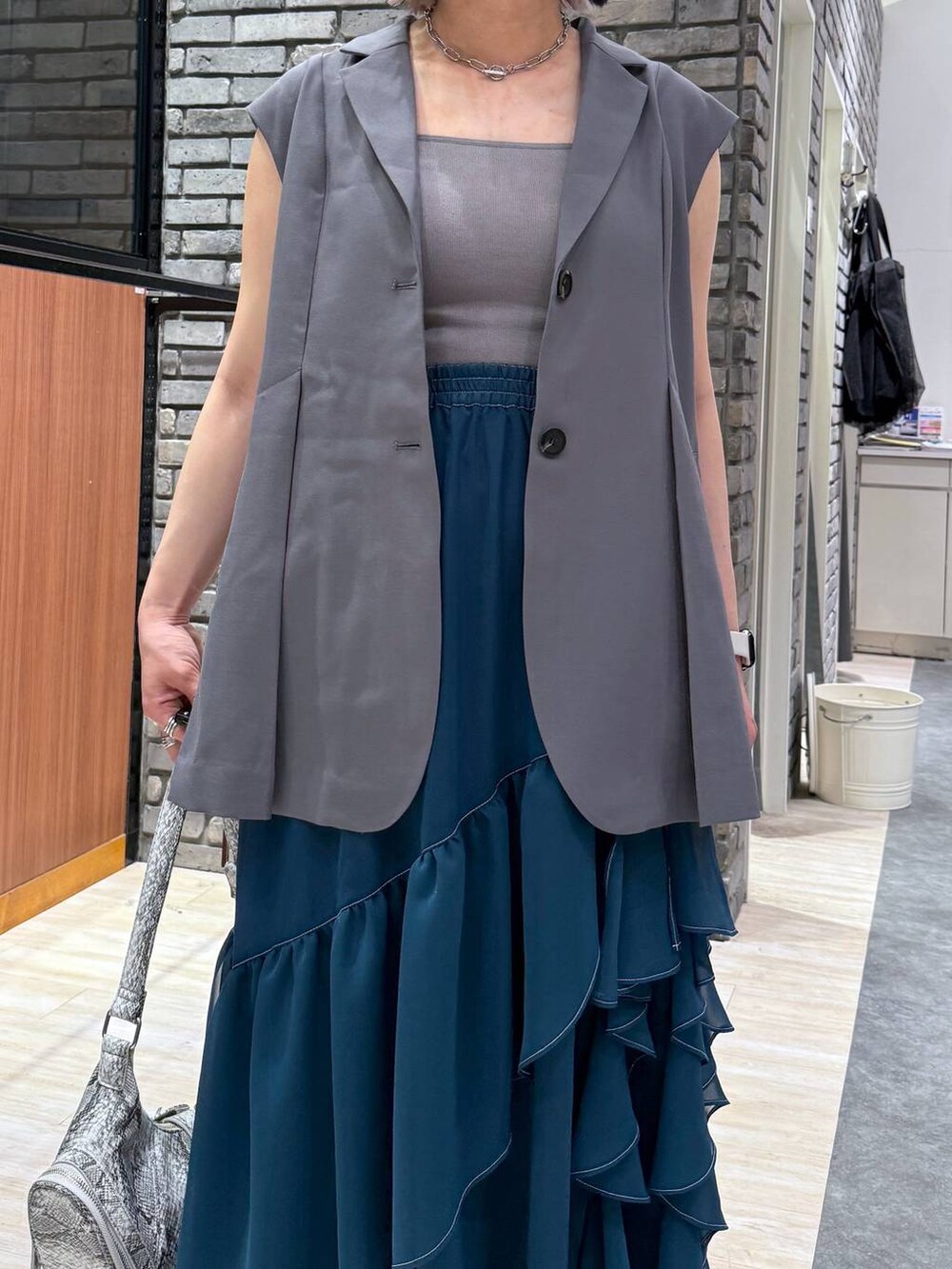 グリーン系のスカート、ブラック系のサンダル、ホワイト系のショルダーバッグを着用したレディースの春コーディネートの3枚目の写真