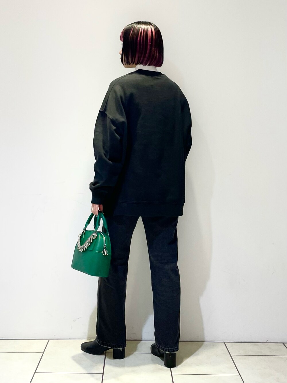 ブラック系のトップス、ホワイト系のニット/セーター、グリーン系のショルダーバッグを着用したレディースの冬コーディネートの4枚目の写真