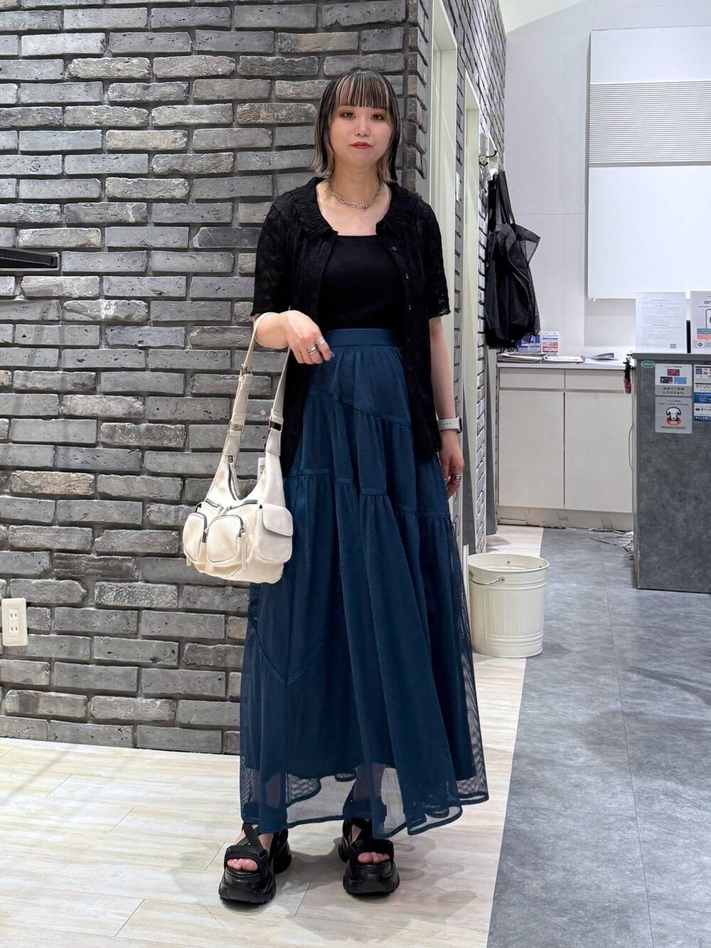 ブラック系のサンダル、ホワイト系のショルダーバッグ、ブルー系のスカートを着用したレディースの春コーディネートの2枚目の写真