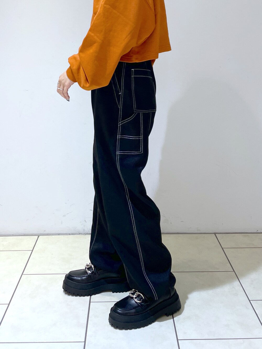 オレンジ系のスウェット、ブラック系のその他パンツ、ブラック系のローファーを着用したレディースの秋コーディネートの5枚目の写真