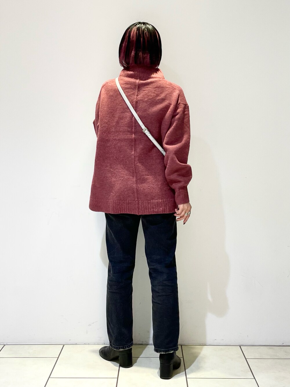 ピンク系のニット/セーター、シルバー系のボストンバッグ、ブラック系のデニムパンツを着用したレディースの春コーディネートの3枚目の写真