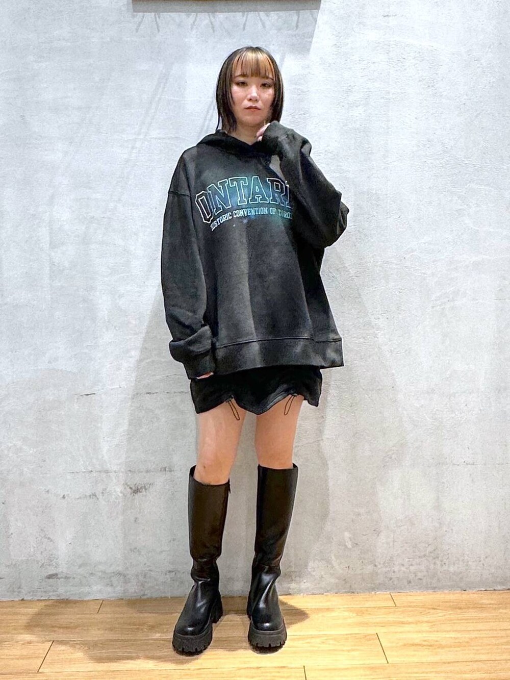 ブラック系のブーツ、ブラック系のパーカー、ブラック系のスカートを着用したレディースの冬コーディネートの2枚目の写真