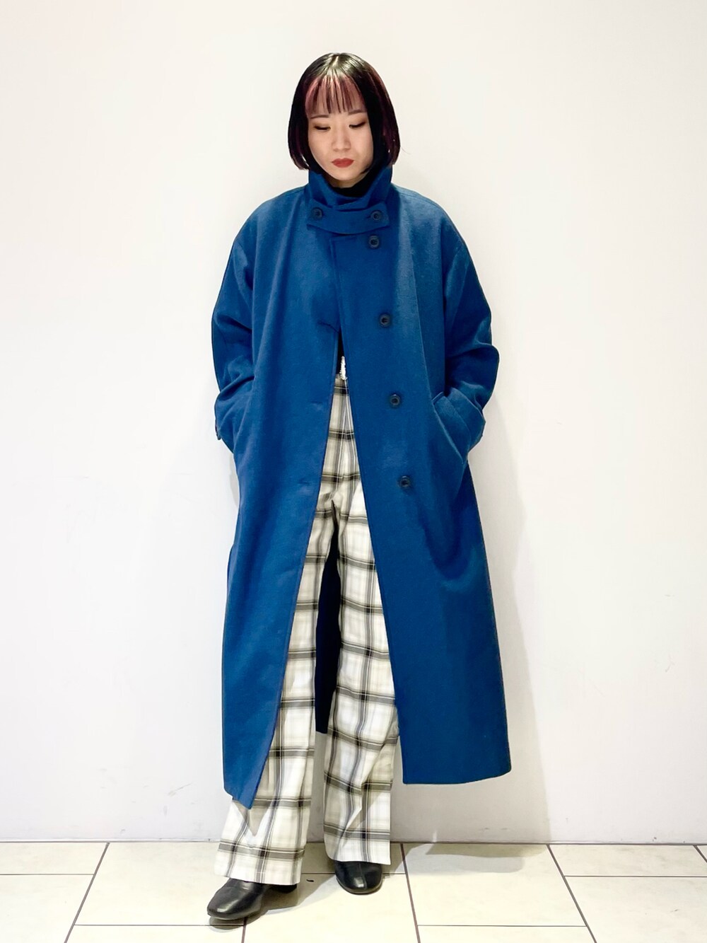 グリーン系のチェスターコート、ブラック系のニット/セーター、ホワイト系のその他パンツを着用したレディースの冬コーディネートの2枚目の写真