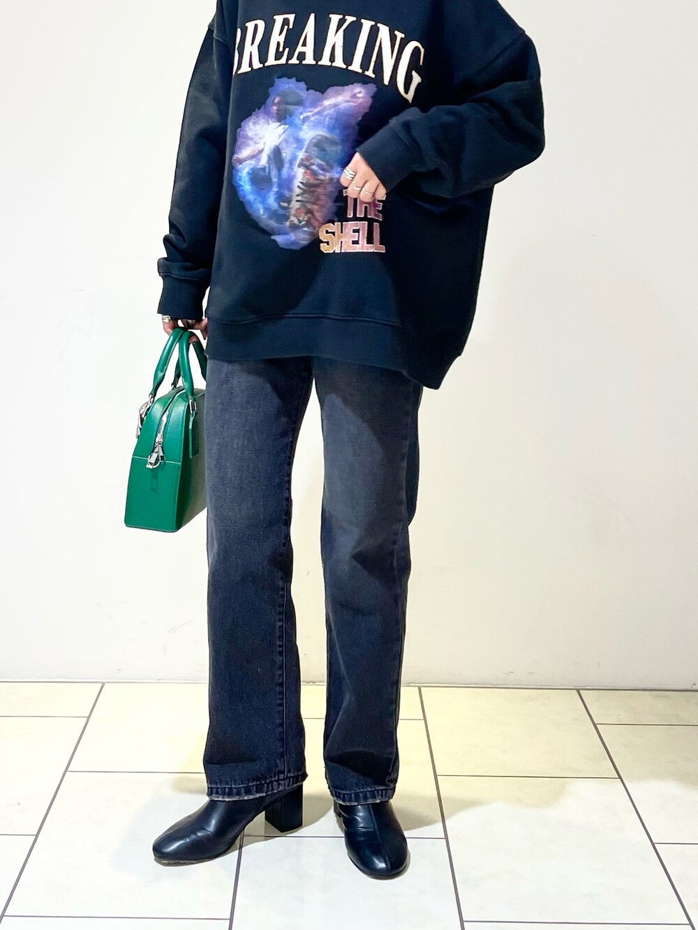 ブラック系のトップス、ホワイト系のニット/セーター、グリーン系のショルダーバッグを着用したレディースの冬コーディネートの5枚目の写真