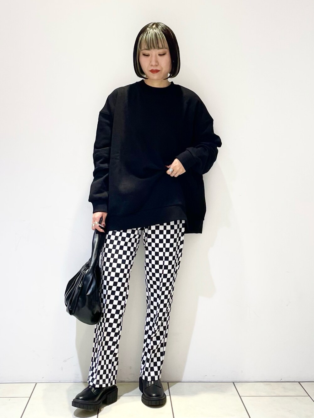 ブラック系のハンドバッグ、ブラック系のブーツ、ブラック系のスウェットを着用したレディースの冬コーディネートの2枚目の写真