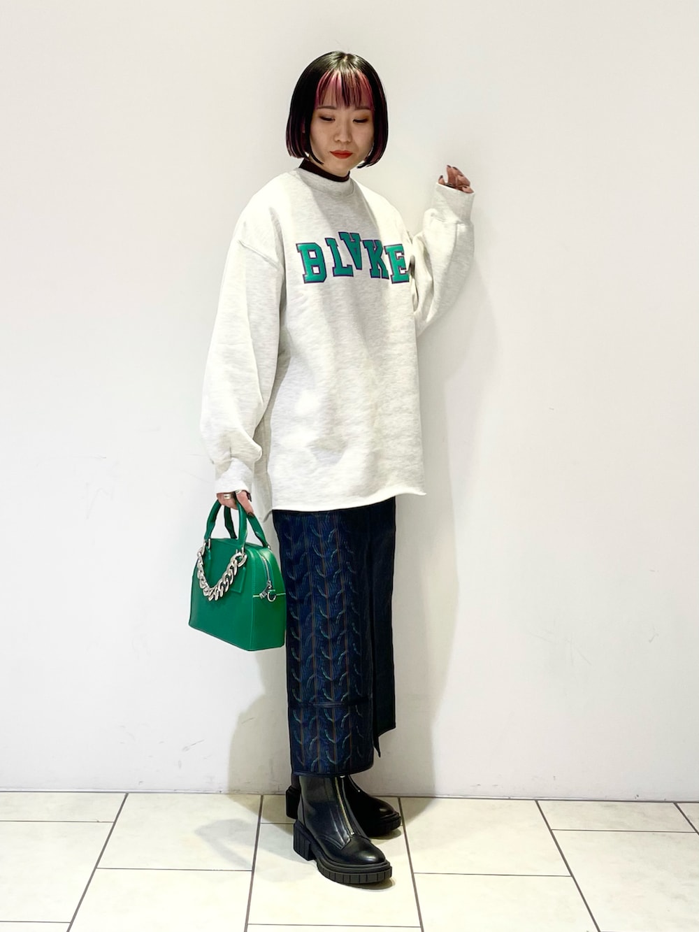 グレー系のスウェット、ブラック系のニット/セーター、グリーン系のショルダーバッグを着用したレディースの冬コーディネートの2枚目の写真