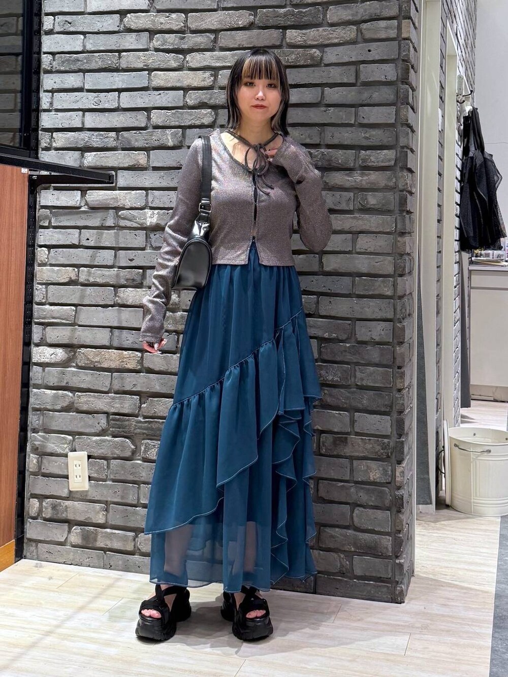 グリーン系のスカート、ブラック系のサンダル、ブラック系のショルダーバッグを着用したレディースの春コーディネートの2枚目の写真
