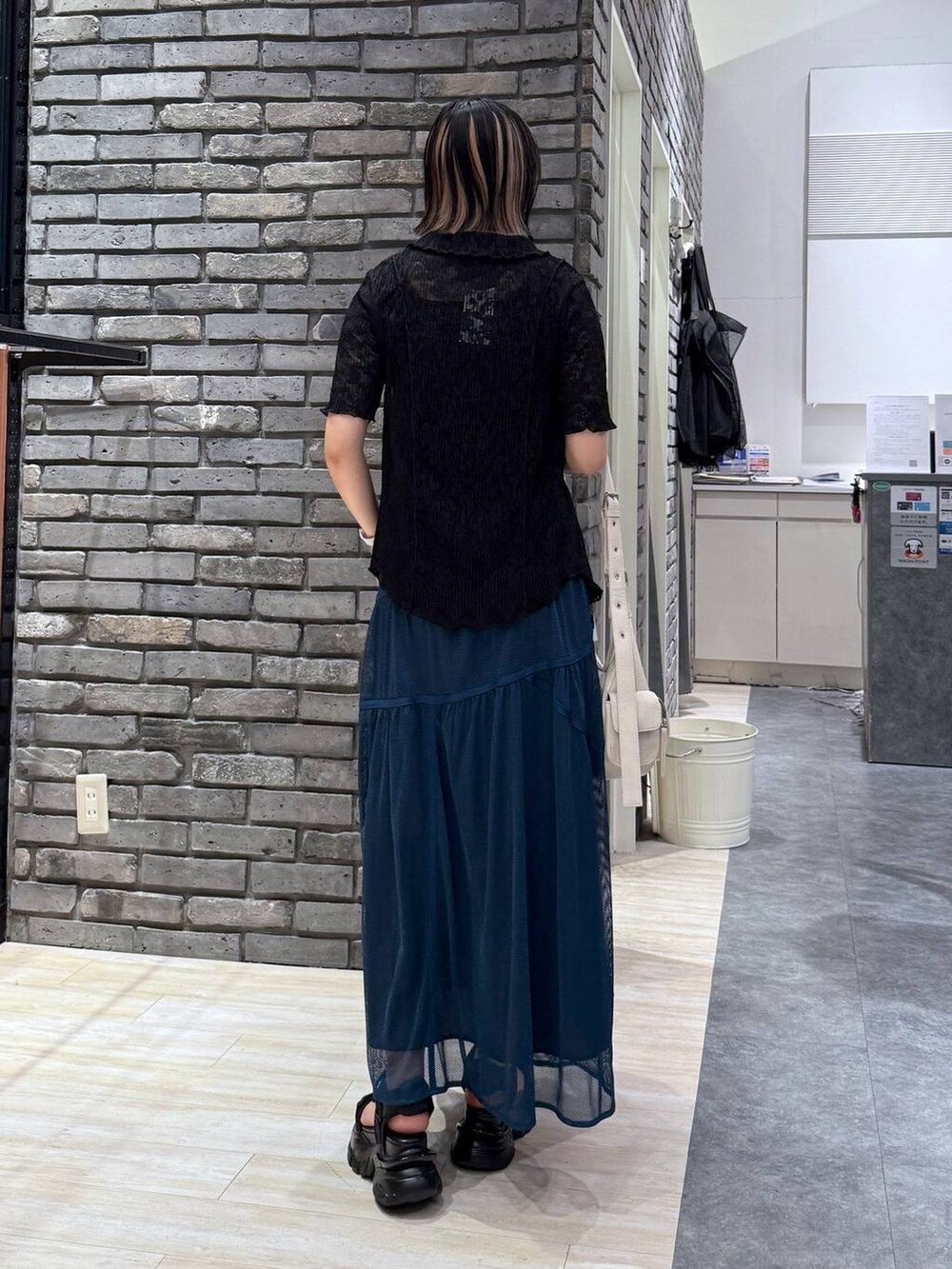 ブラック系のサンダル、ホワイト系のショルダーバッグ、ブルー系のスカートを着用したレディースの春コーディネートの4枚目の写真