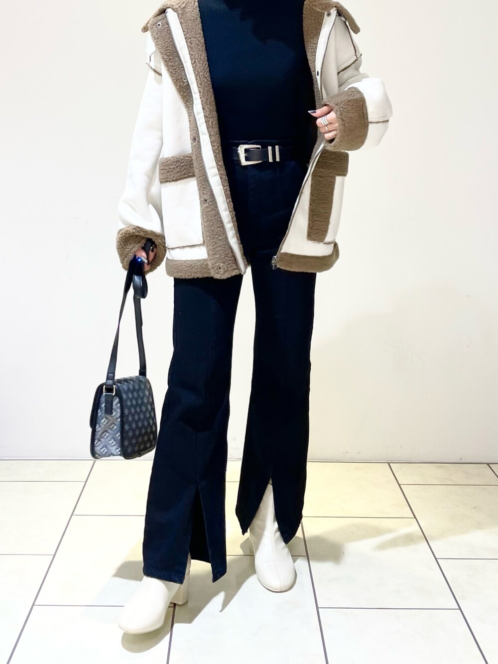 ベージュ系のブルゾン、ブラック系のニット/セーター、ブラック系のデニムパンツを着用したレディースの冬コーディネートの4枚目の写真