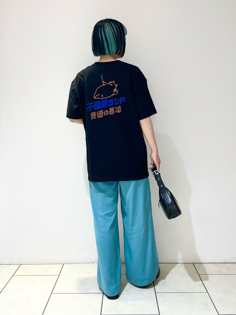 ブルー系のスラックス、ブラック系のショルダーバッグ、ブラック系のローファーを着用したレディースの夏コーディネートの2枚目の写真