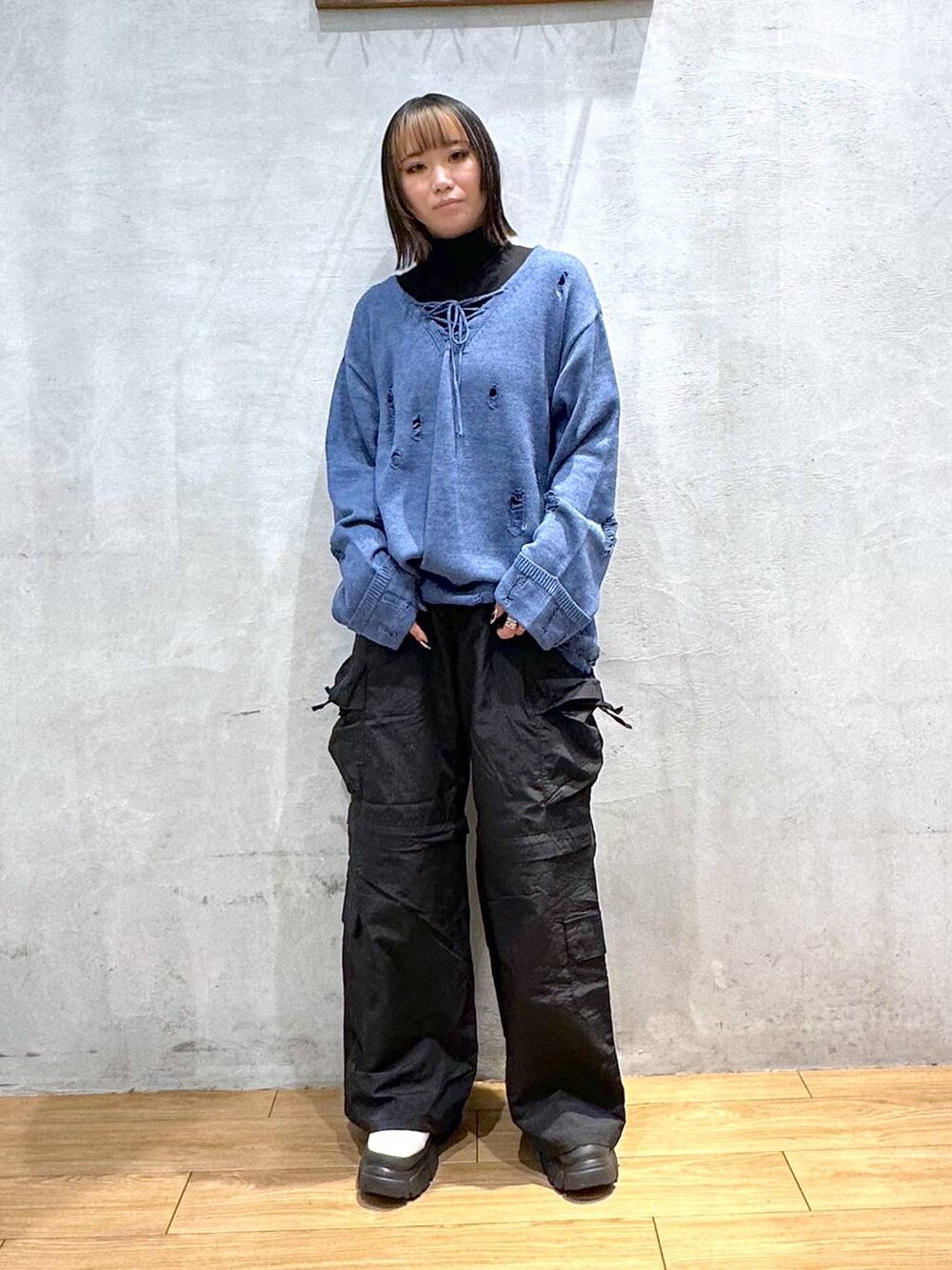 ブルー系のニット/セーター、ホワイト系のブーツ、ブラック系のカーゴパンツを着用したレディースの冬コーディネートの2枚目の写真