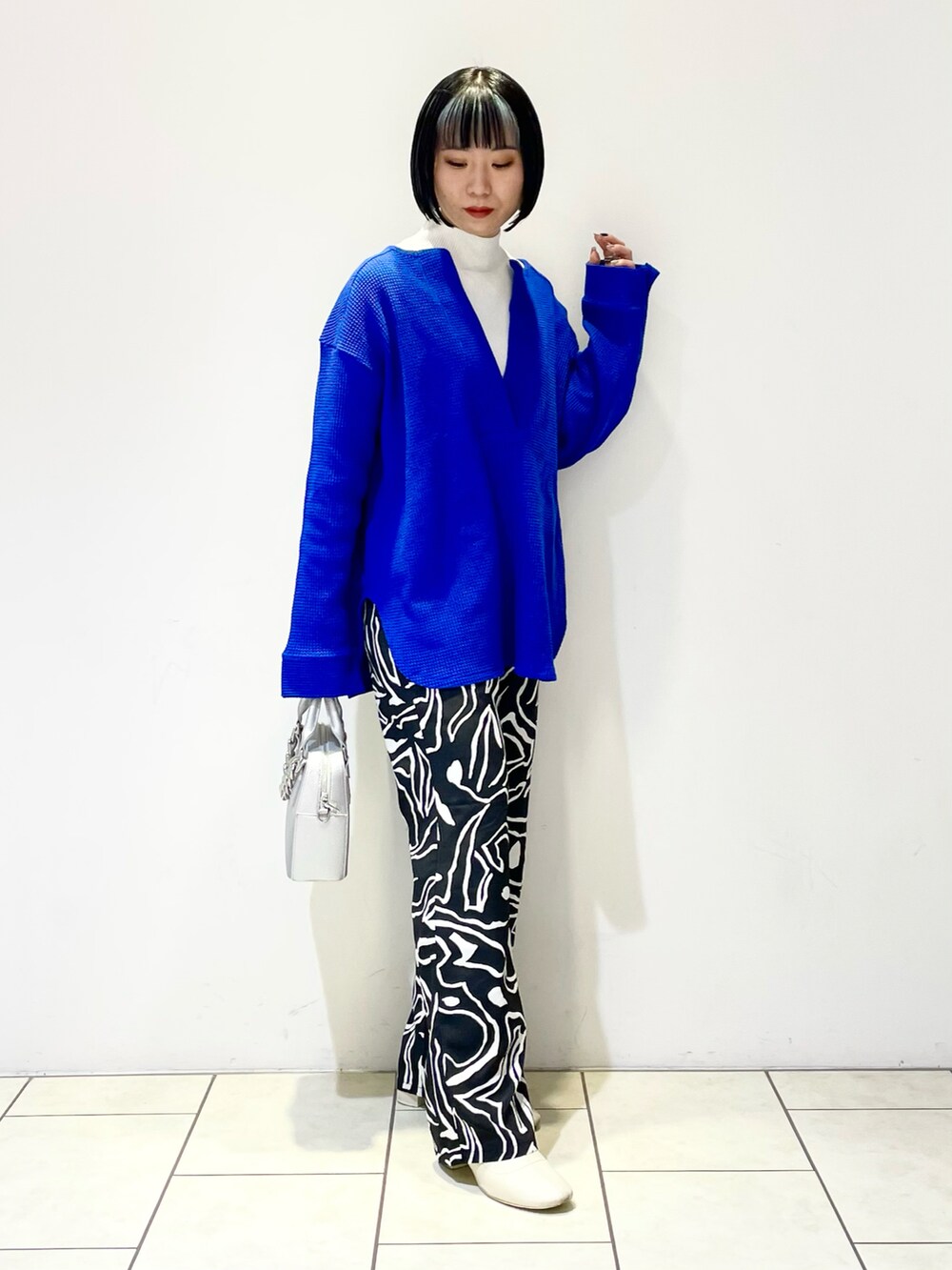 ブルー系のTシャツ/カットソー、ホワイト系のニット/セーター、シルバー系のショルダーバッグを着用したレディースの春コーディネートの2枚目の写真