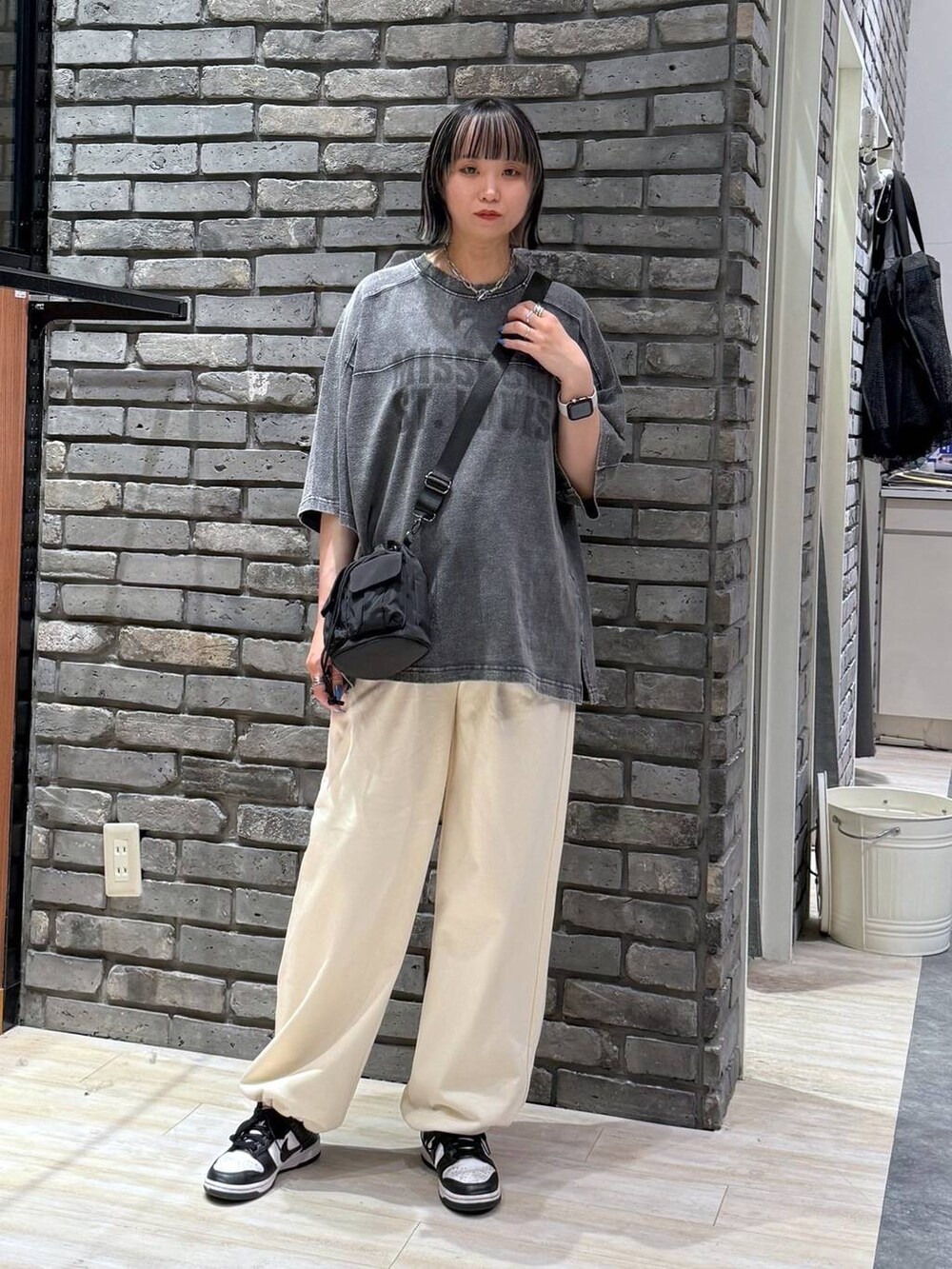 ブラック系のショルダーバッグ、ブラック系のTシャツ/カットソー、ホワイト系のスウェットパンツを着用したレディースの春コーディネートの3枚目の写真