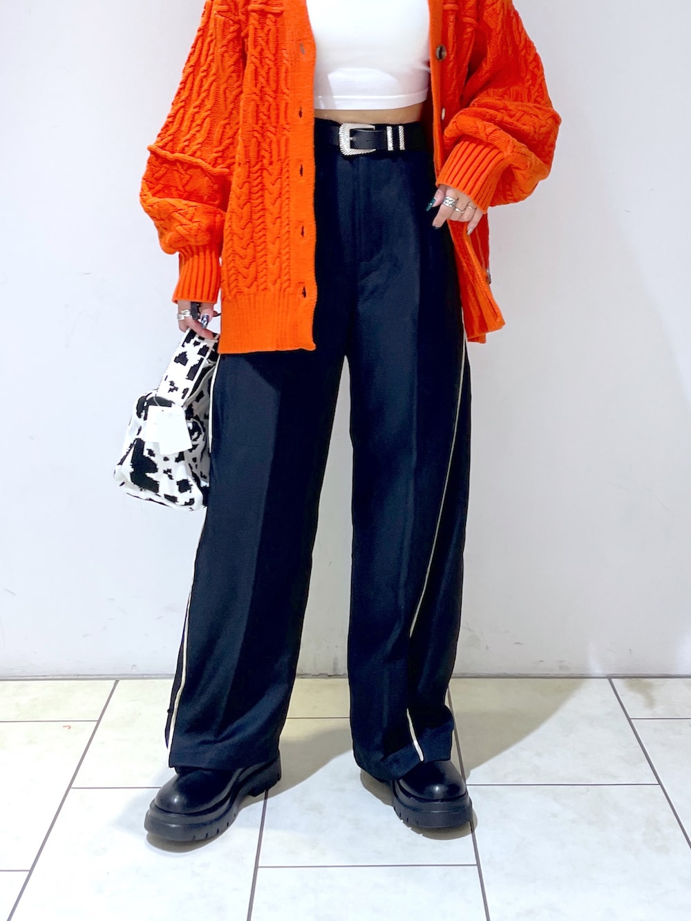 オレンジ系のカーディガン/ボレロ、ホワイト系のキャミソール、ブラック系のスラックスを着用したレディースの秋コーディネートの5枚目の写真
