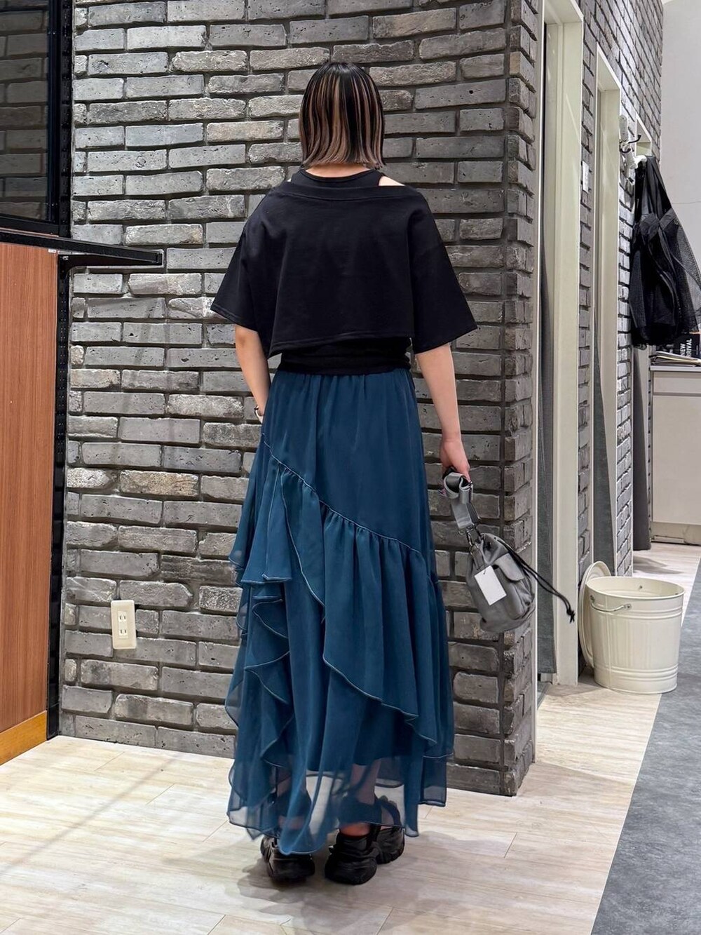 グリーン系のスカート、ブラック系のサンダル、ベージュ系のショルダーバッグを着用したレディースの春コーディネートの3枚目の写真