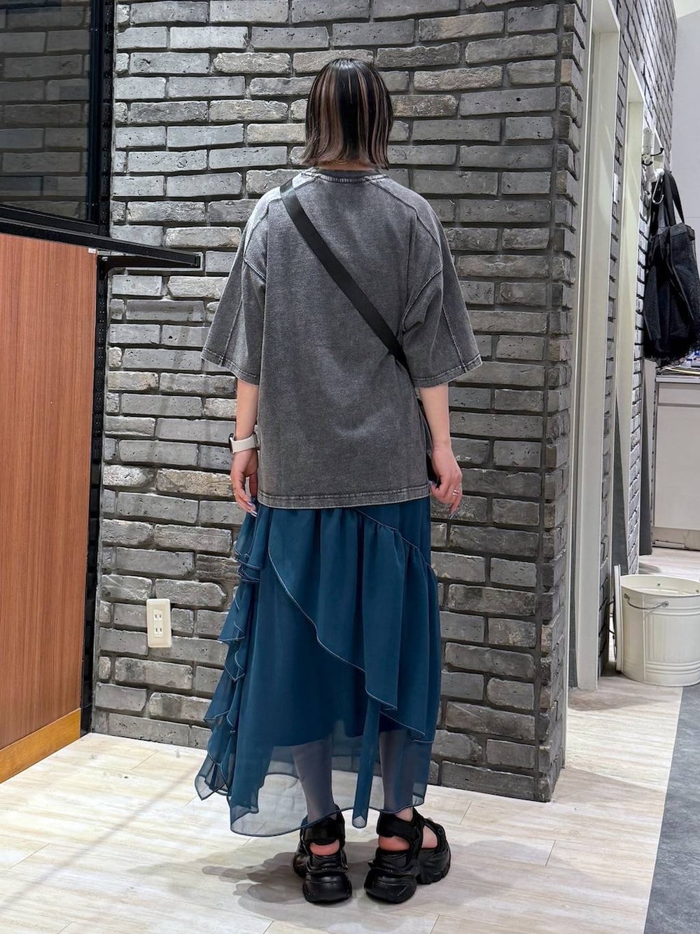 グリーン系のスカート、ブラック系のサンダル、ブラック系のショルダーバッグを着用したレディースの春コーディネートの4枚目の写真