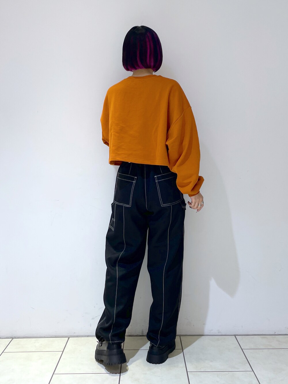 オレンジ系のスウェット、ブラック系のその他パンツ、ブラック系のローファーを着用したレディースの秋コーディネートの3枚目の写真