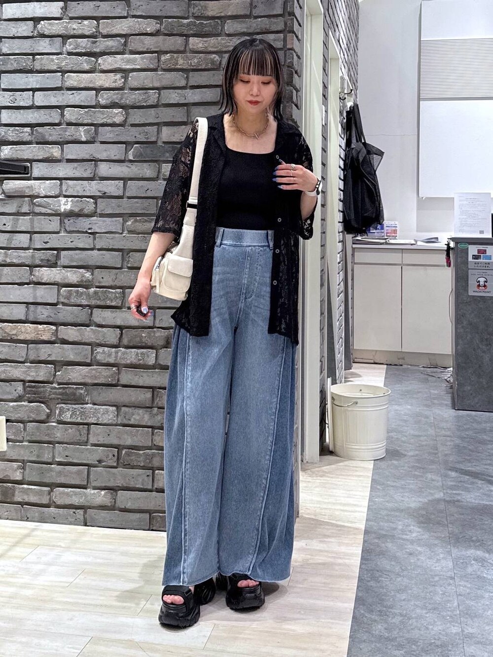 ブラック系のサンダル、ブルー系のデニムパンツ、ホワイト系のショルダーバッグを着用したレディースの春コーディネートの2枚目の写真