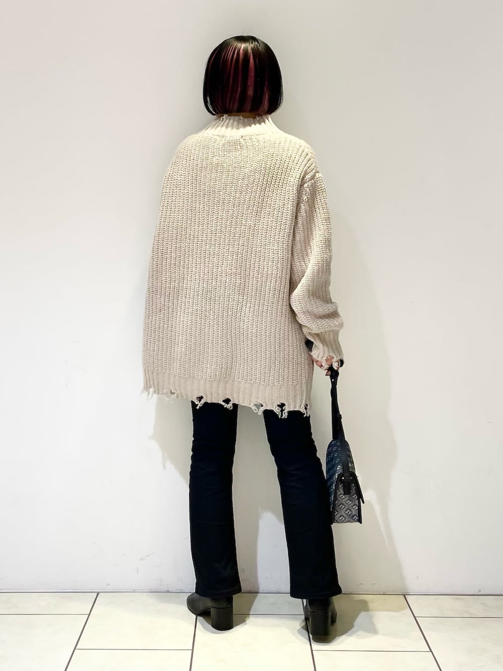 ベージュ系のニット/セーター、ホワイト系のTシャツ/カットソー、ブラック系のショルダーバッグを着用したレディースの冬コーディネートの3枚目の写真