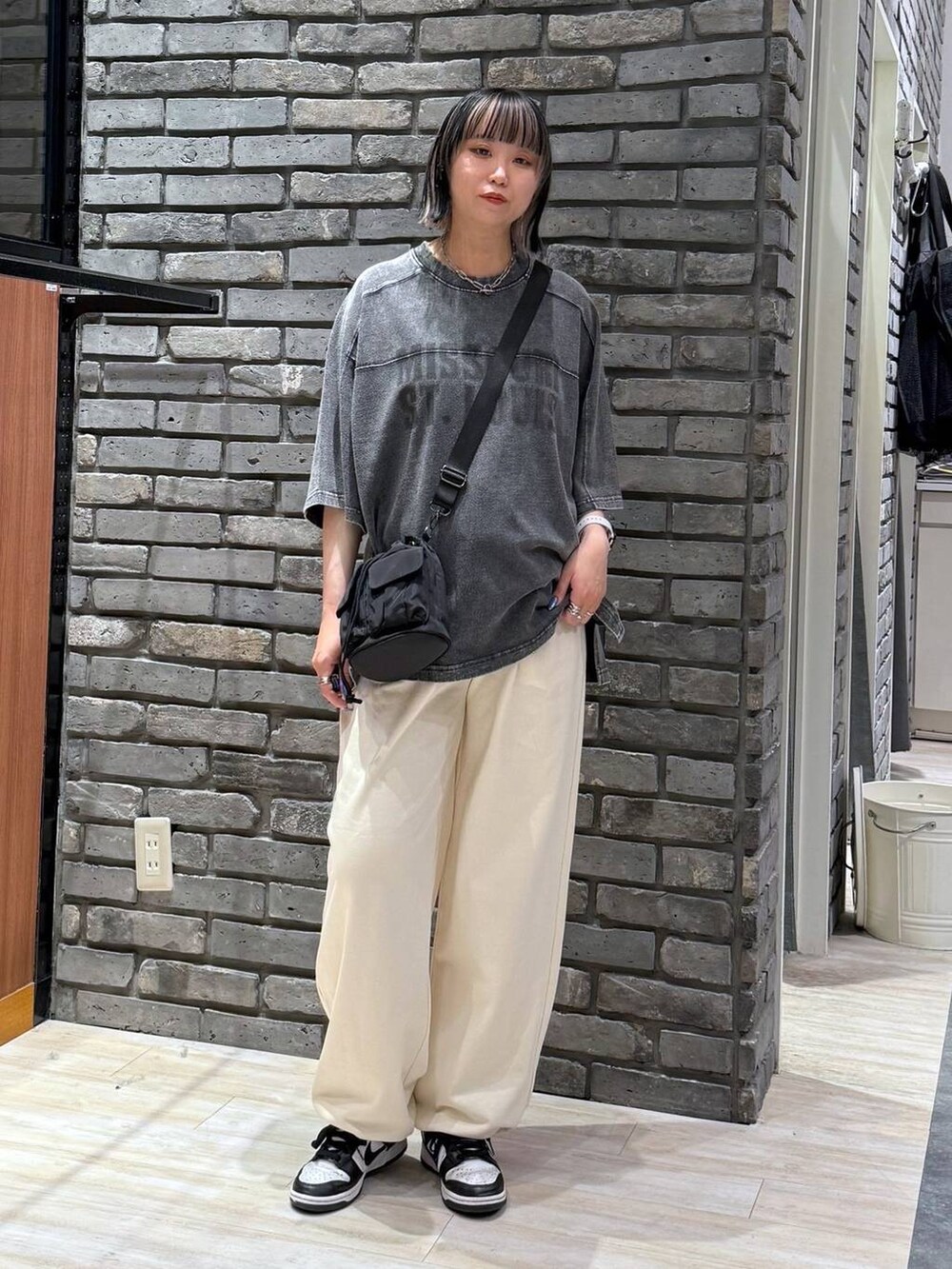 ブラック系のショルダーバッグ、ブラック系のTシャツ/カットソー、ホワイト系のスウェットパンツを着用したレディースの春コーディネートの2枚目の写真