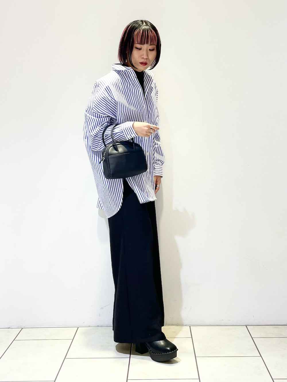 ブラック系のニット/セーター、ブルー系のシャツ/ブラウス、ブラック系のボストンバッグを着用したレディースの春コーディネートの3枚目の写真