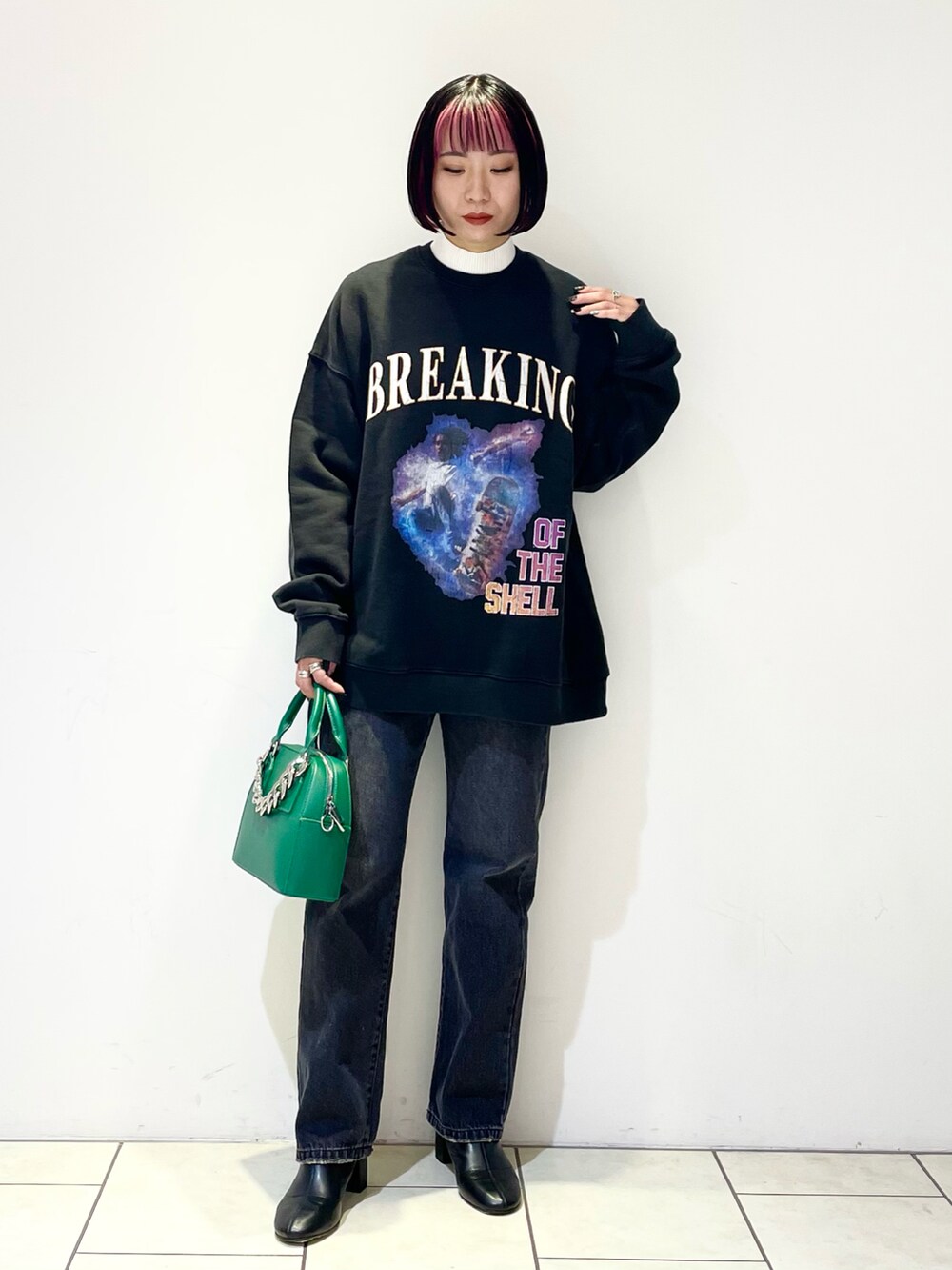 ブラック系のトップス、ホワイト系のニット/セーター、グリーン系のショルダーバッグを着用したレディースの冬コーディネートの2枚目の写真