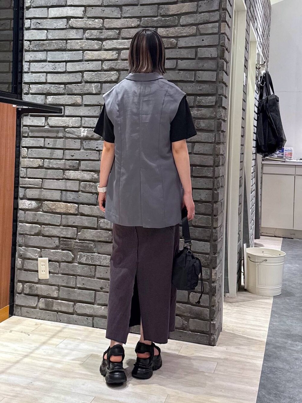 ブラック系のサンダル、ブラック系のショルダーバッグ、グレー系のベストを着用したレディースの春コーディネートの3枚目の写真