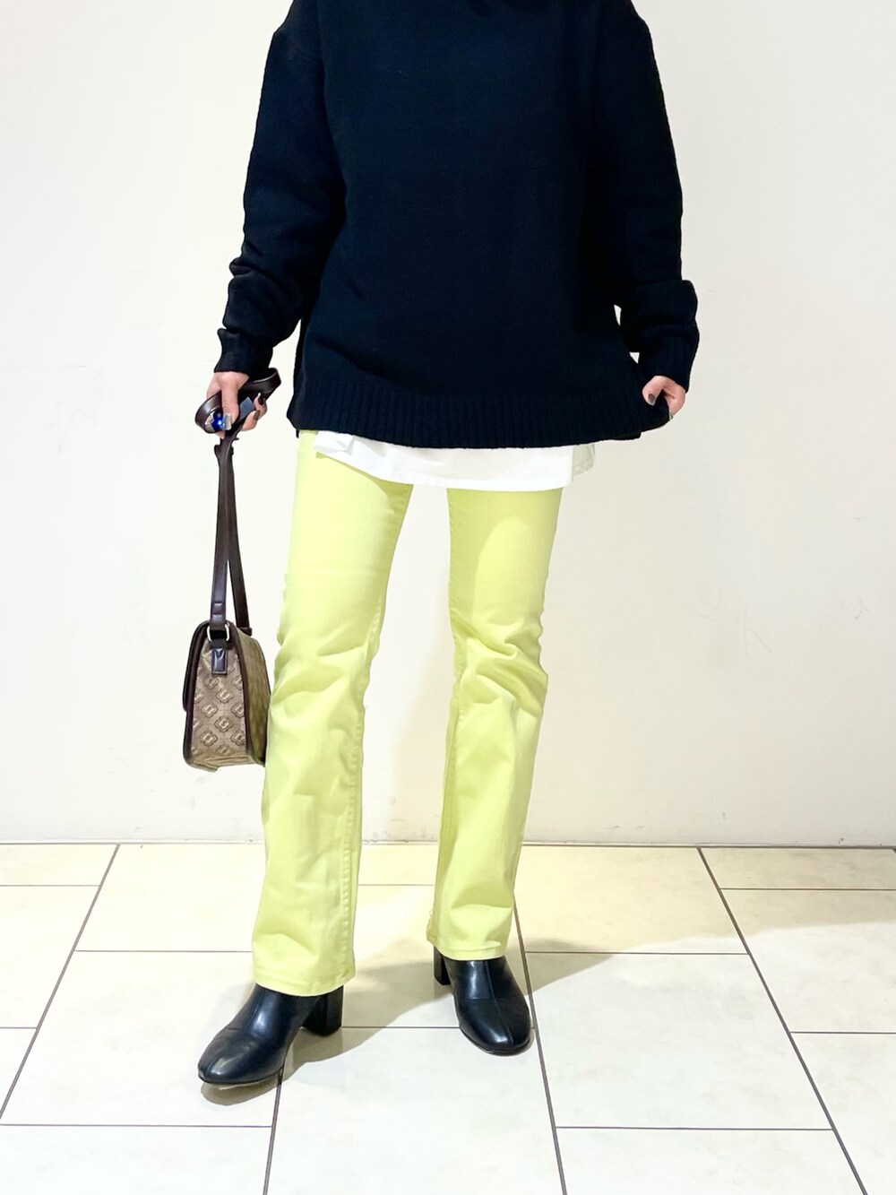 ブラック系のニット/セーター、ホワイト系のTシャツ/カットソー、ブラウン系のショルダーバッグを着用したレディースの春コーディネートの4枚目の写真