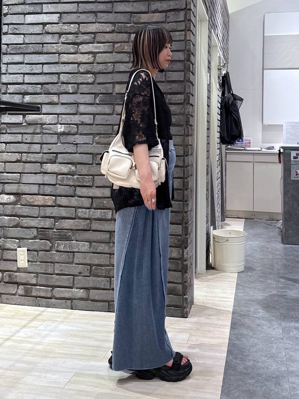 ブラック系のサンダル、ブルー系のデニムパンツ、ホワイト系のショルダーバッグを着用したレディースの春コーディネートの3枚目の写真