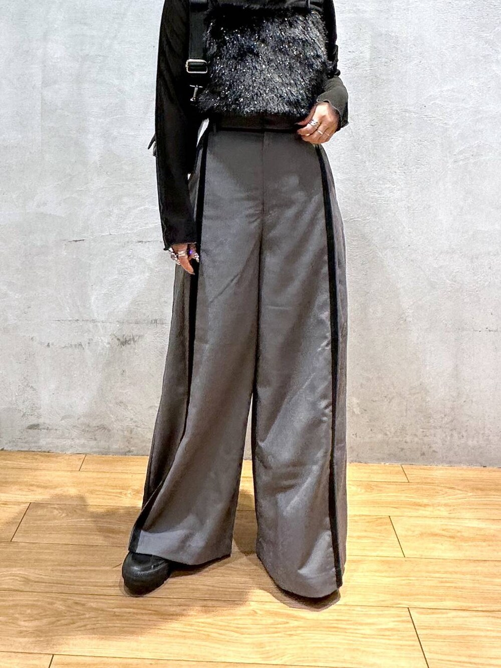 グレー系のスラックス、ブラック系のショルダーバッグ、ブラック系のベストを着用したレディースの秋コーディネートの2枚目の写真